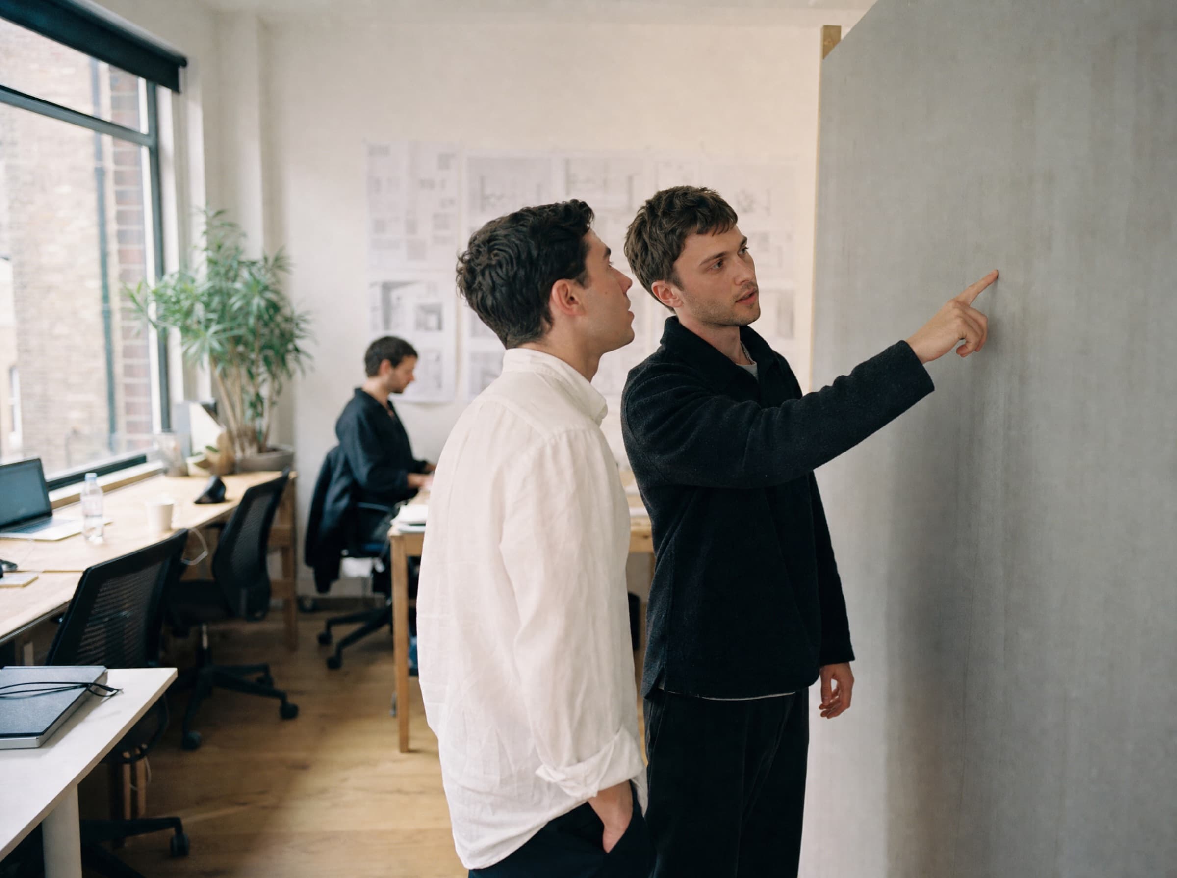Two colleagues working through a plan on a wall panel together